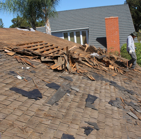 Man standing on a damaged roof, repairing a home