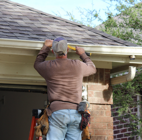 Roof repair contractor on a ladder, working on a home's roof