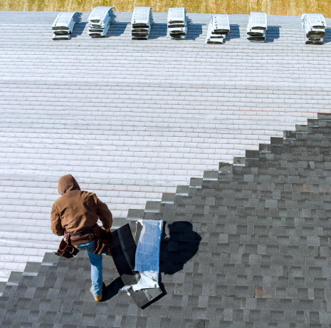 Aerial view of a man standing on top of a roof, engaged in roof repair